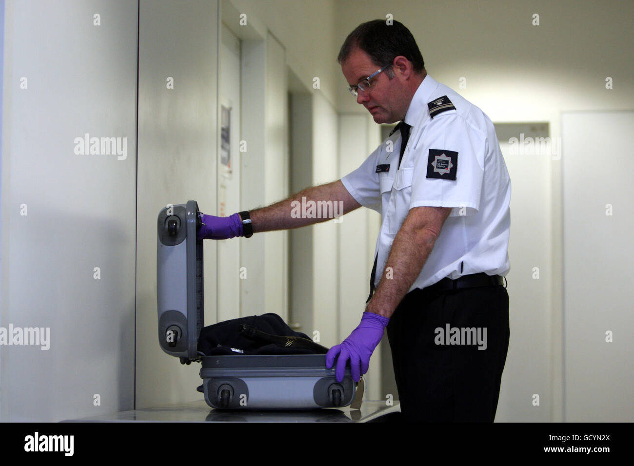 Grant Miller Assistant Director of the UK Border Agency Heathrow searches through luggage at Heathrow Airport. PRESS ASSOCIATION Photo. Picture date: Thursday January 6, 2011. Border staff use a range of methods and specialist equipment to detect drugs being smuggled into Britain. Sniffer dogs are trained to identify certain drugs and cash while x-ray machines can reveal unusual luggage or parcels. A low-dose radiation body-scanner can be used to detect whether mules have swallowed or stashed packets of drugs. Officials also act on tip-offs from members of the public, criminal informants and Stock Photo