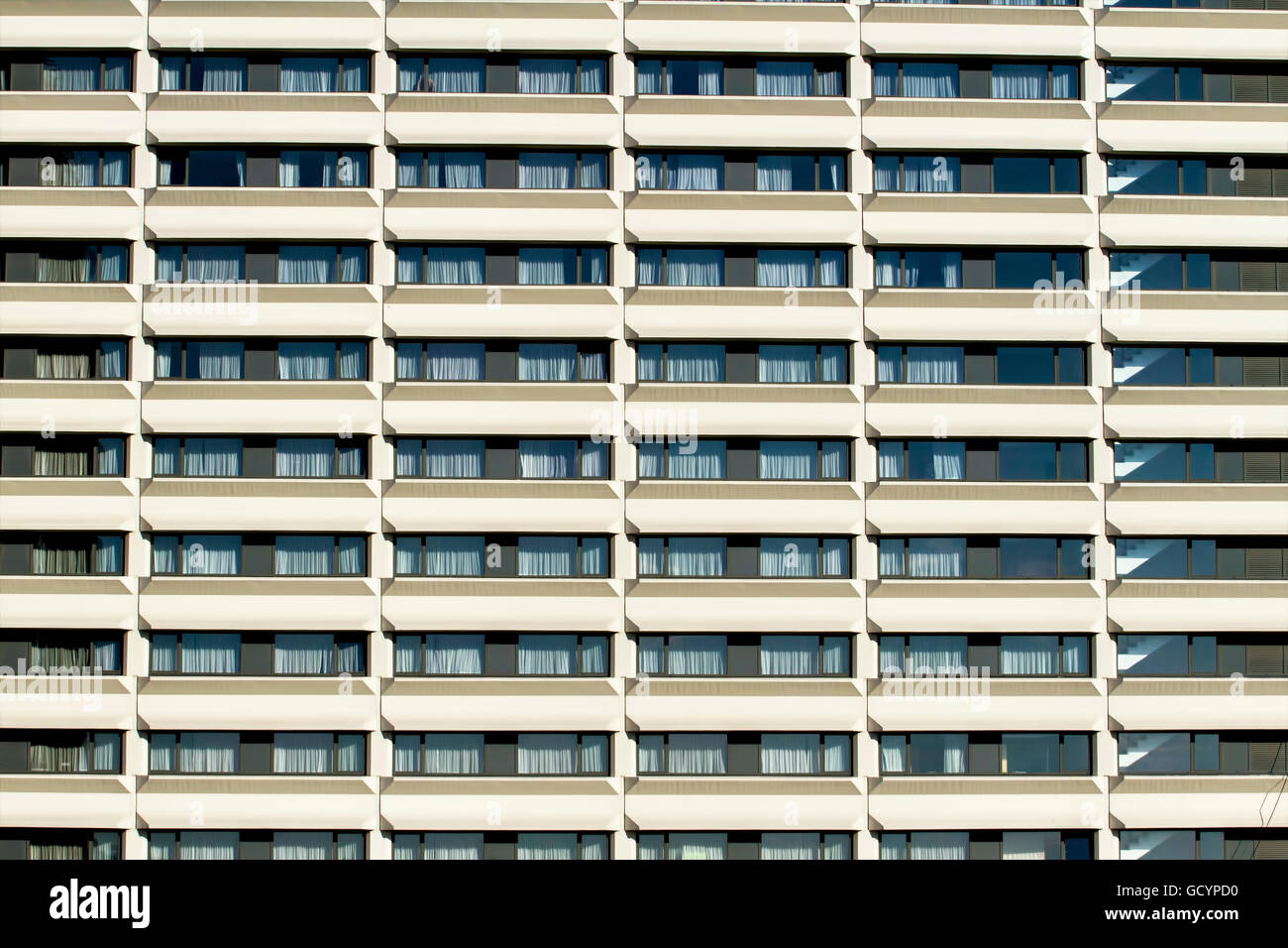Modern building front wall with repeating pattern of windows and balcony for background Stock Photo