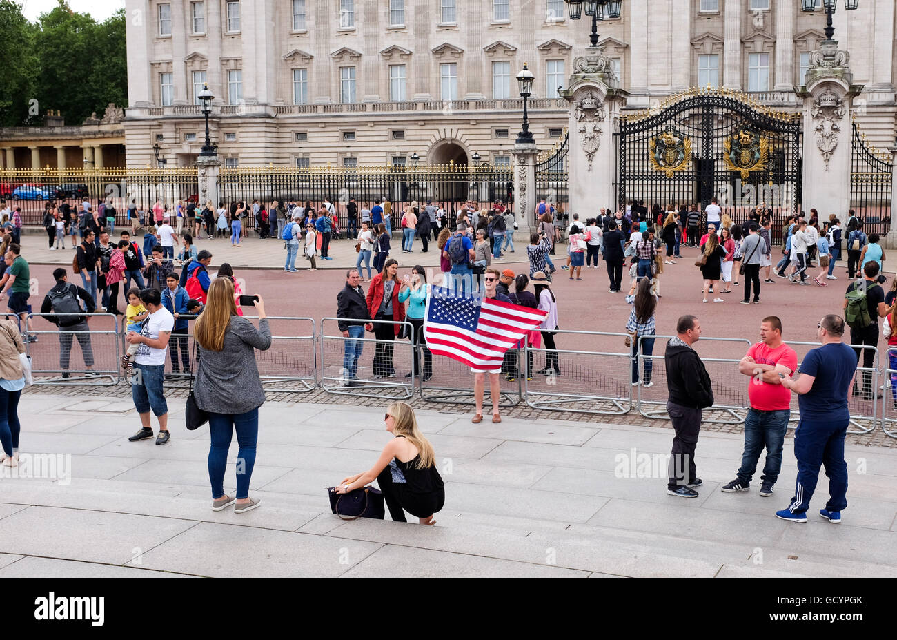 Tourists with an American flag of the stars and stripes taking selfie photographs outside Buckingham Palace London UK Stock Photo