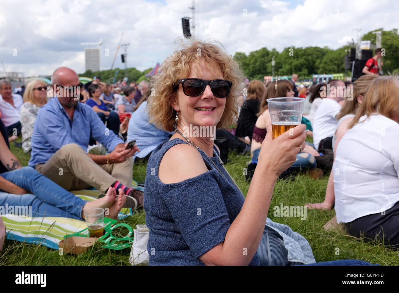 Woman enjoying a pint of beer outside in a plastic glass in summer UK Stock Photo