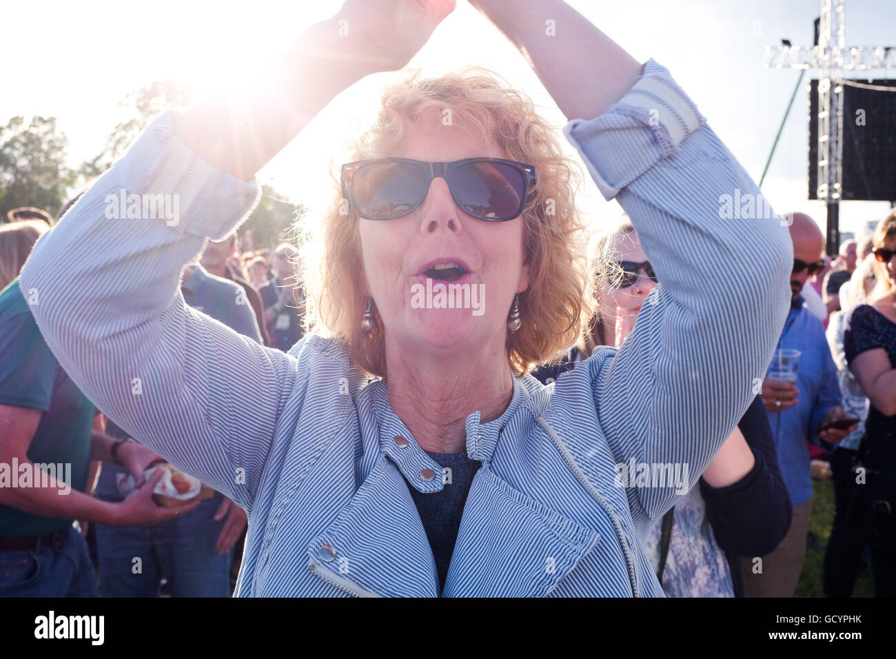 Mature woman cheering at a rock concert in a crowd UK Stock Photo