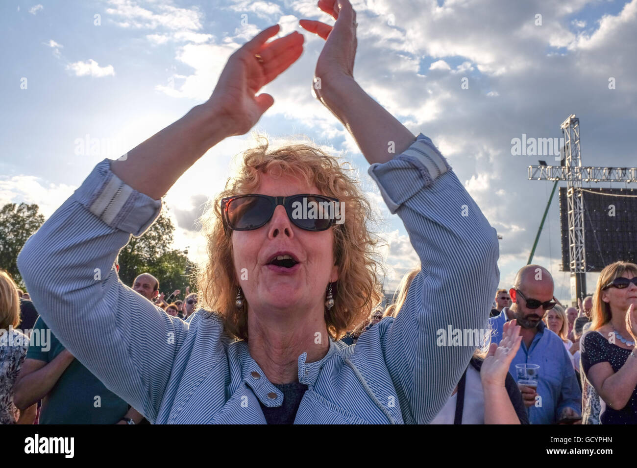 Mature woman cheering at a rock concert in a crowd UK Stock Photo