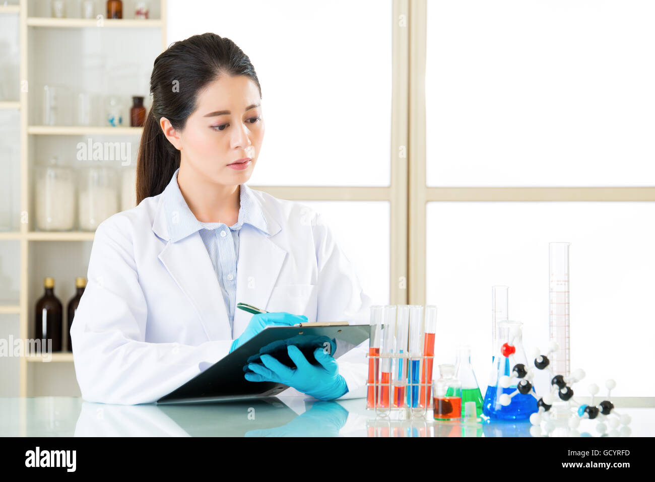Asian female scientist recording her research data write on clipboard