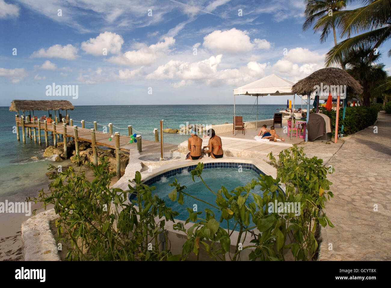 Tourists at swimming pool and spa of Hotel Compass Point Resort at Love beach Nassau, Bahamas, Caribbean. Brightly Colored Cotta Stock Photo