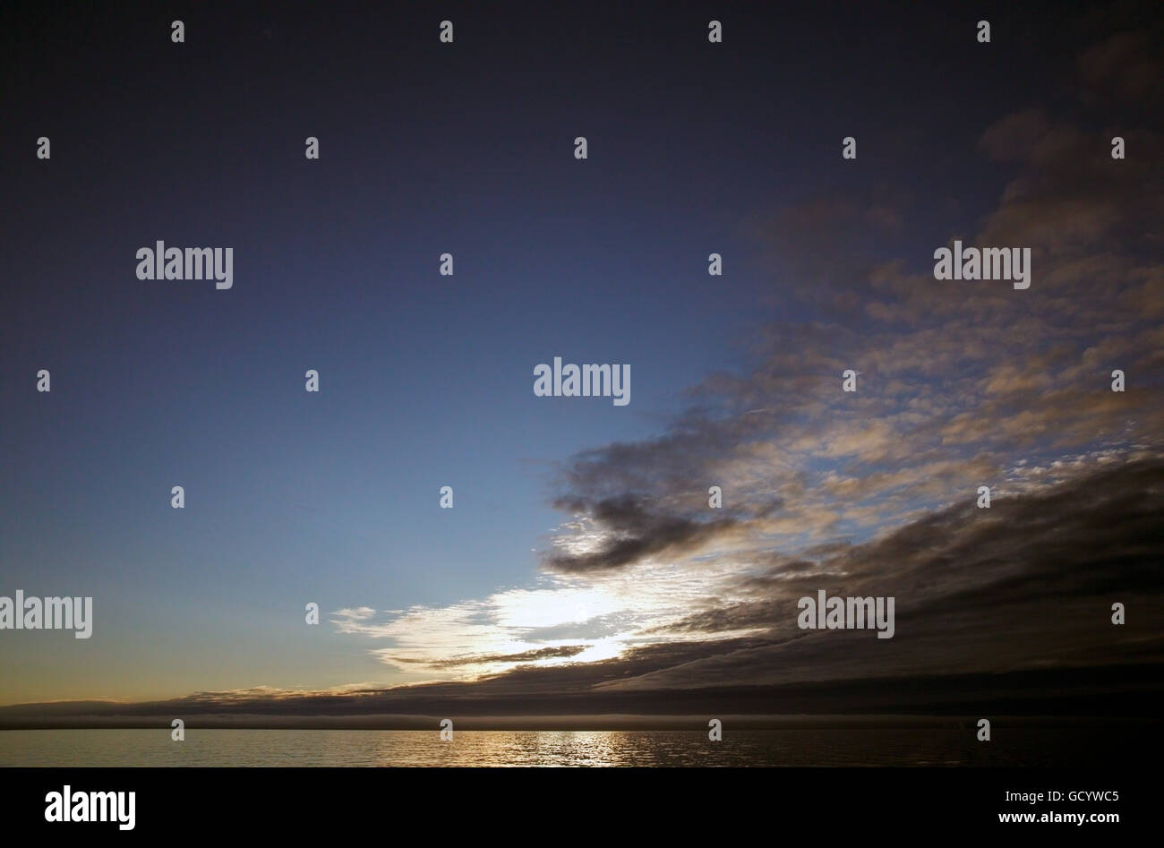 The midnight sun behind cloud bank off the west coast of Greenland Stock Photo