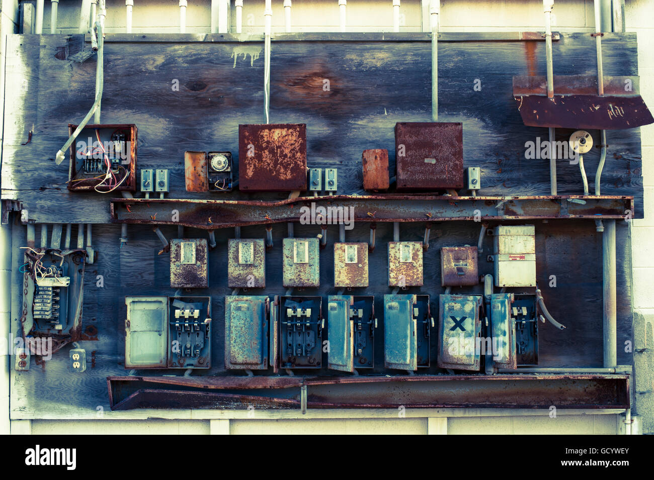 Electrical boxes outside on side of building rusting, damaged and dangerous Stock Photo