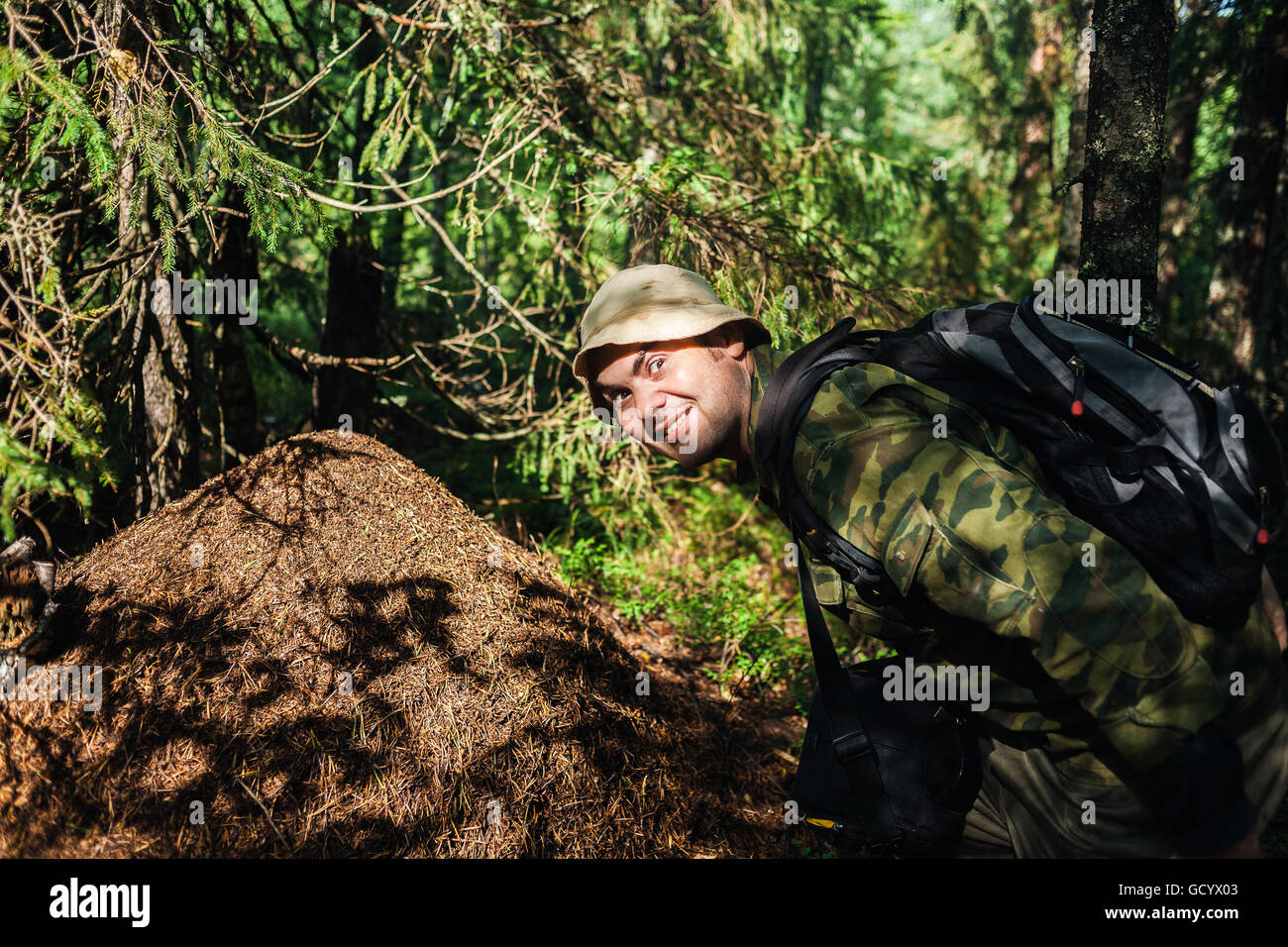 the man naturalist has found a big ant hill in forest and shows it to us Stock Photo