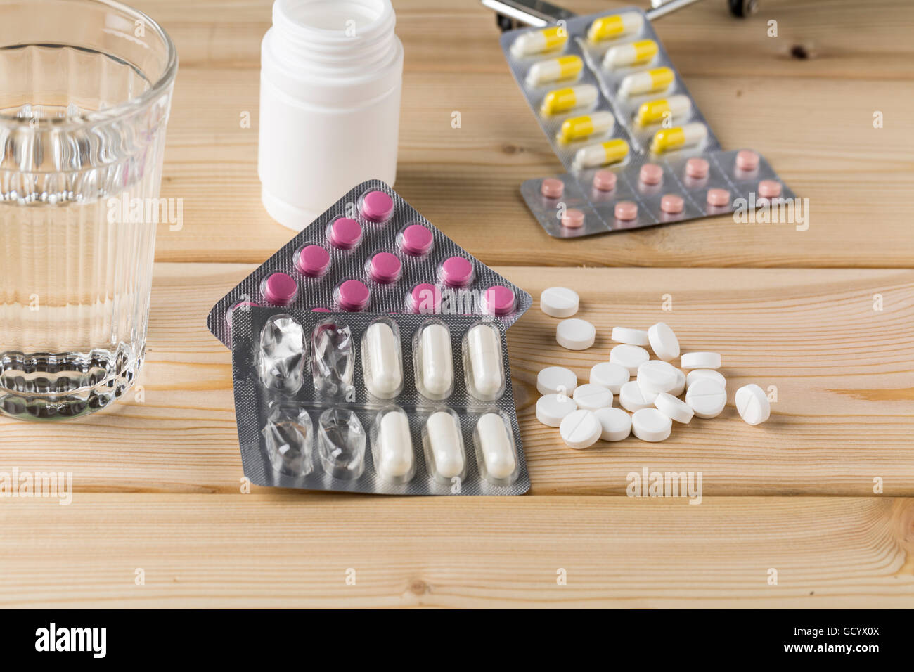 Glass of clean water and pill blister packs on wooden table Stock Photo