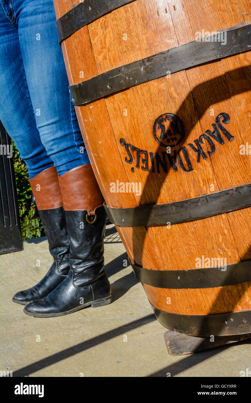 A Woman's legs in tight jeans tucked into riding boots along side an upside down Jack Daniel's oak barrel with metal bands Stock Photo