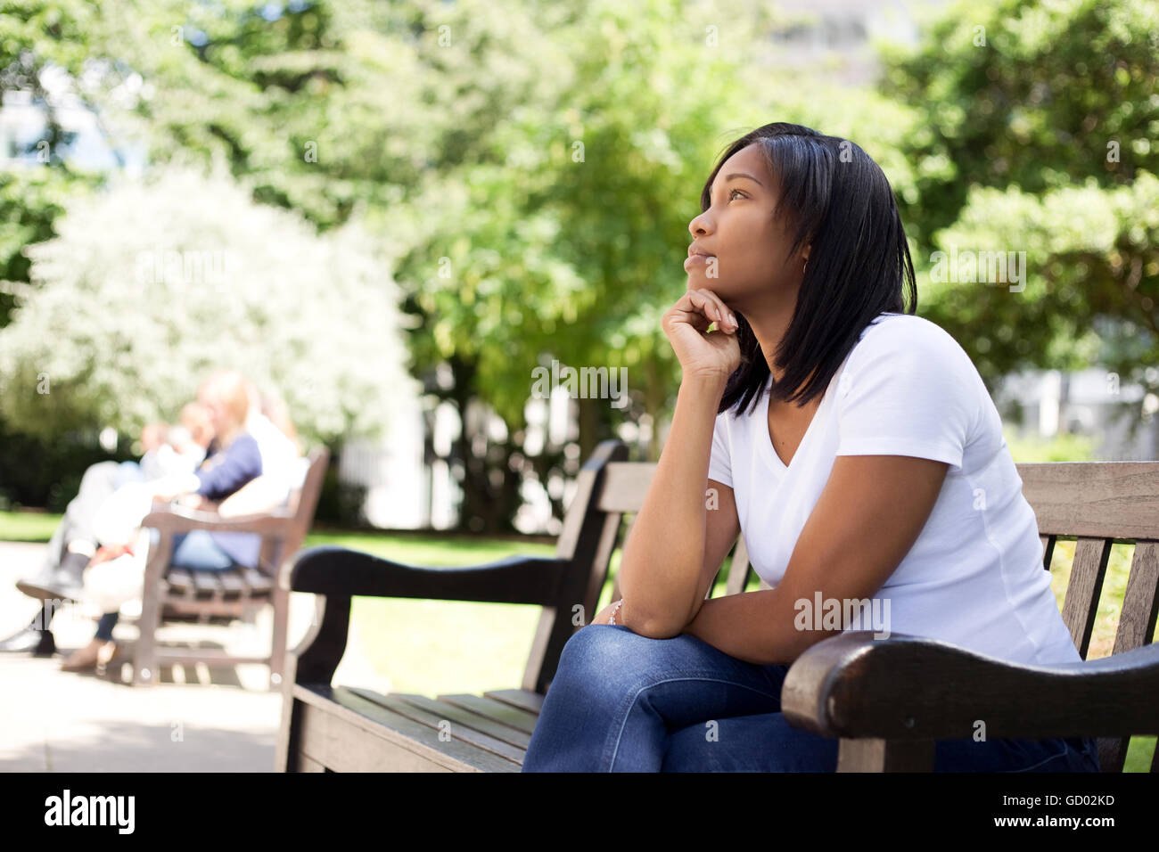 young woman sitting on a bench in a park Stock Photo - Alamy
