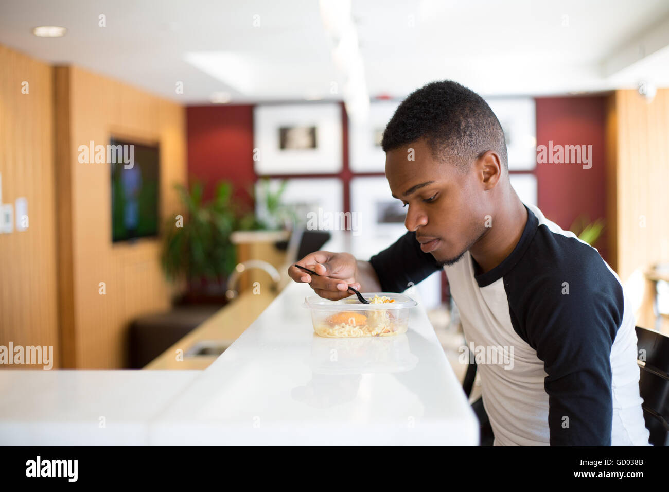 Closeup portrait young handsome man eating noodles, sitting at white table, isolated luxurious, urban indoor background Stock Photo