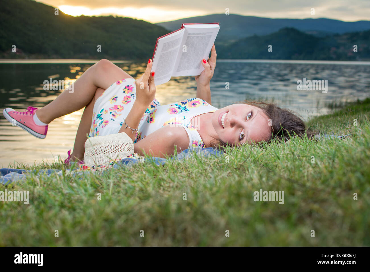 Young woman reading a book by the lake. Solo relaxation Stock Photo