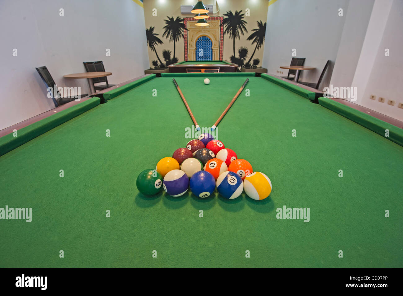 Closeup of billiard balls on green felt table with pool cues in games room Stock Photo
