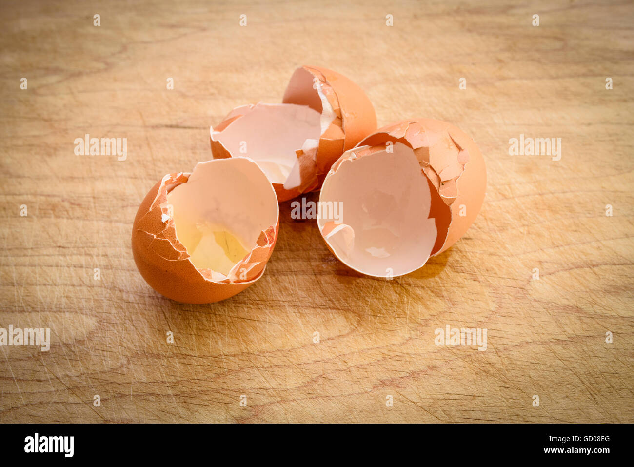 Three broken eggshells on a wooden board Stock Photo