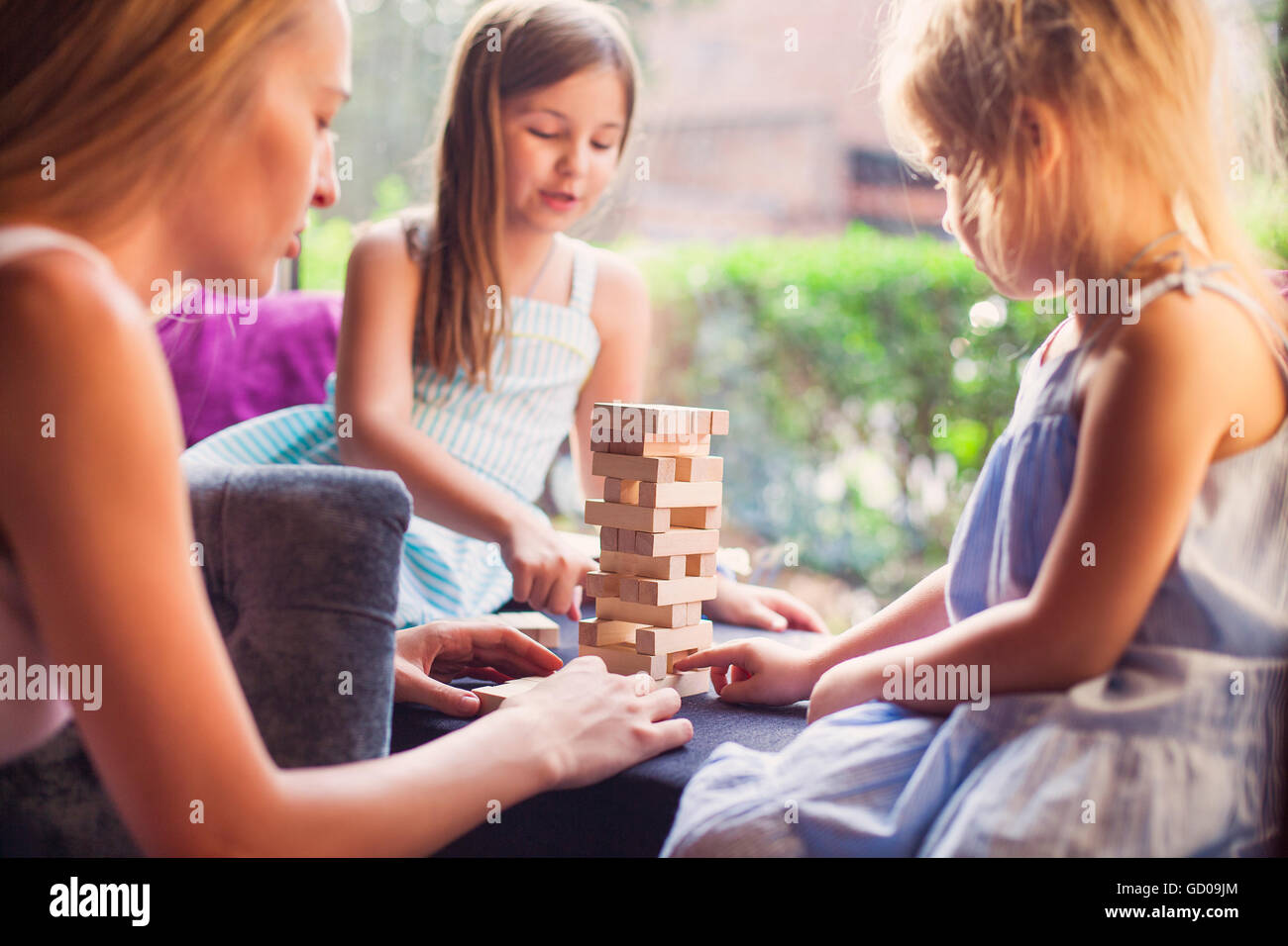 Happy mother with two children playing the wooden blocks tower at home ...