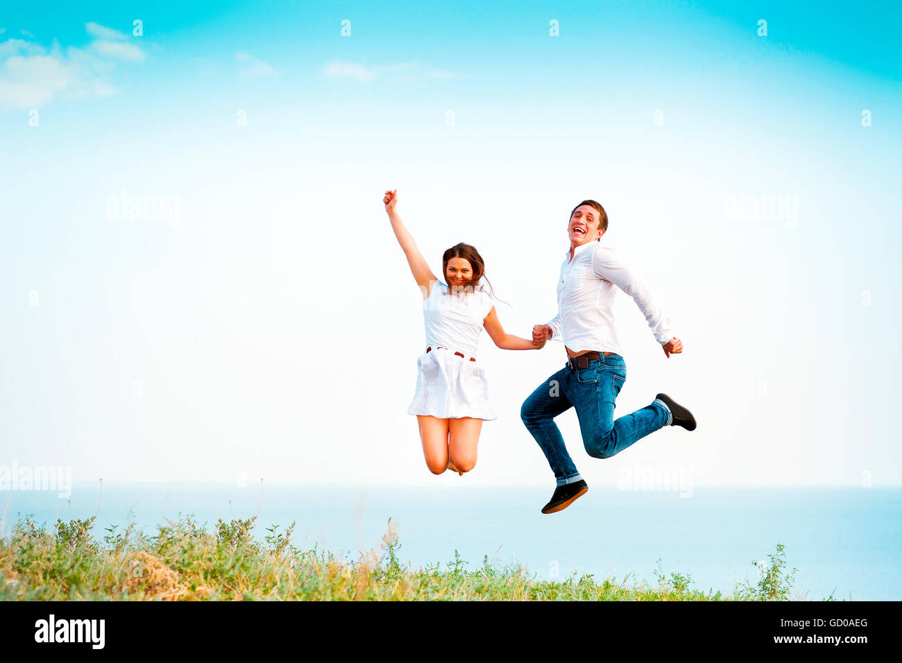 Young happy couple jumping on the beach holding hands Stock Photo - Alamy