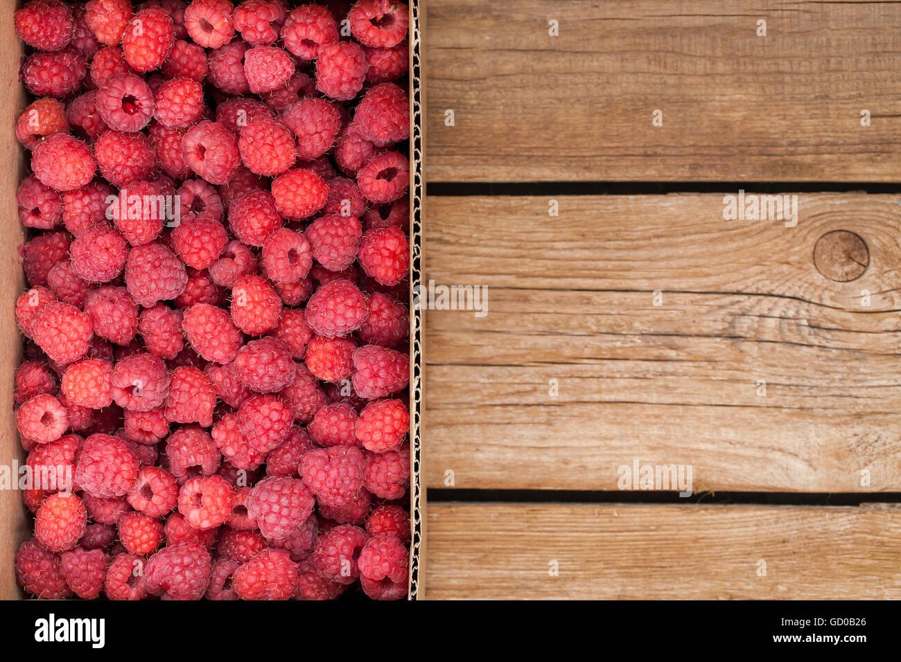 Fresh organic ripe raspberry in box on wooden table with copy space Stock Photo