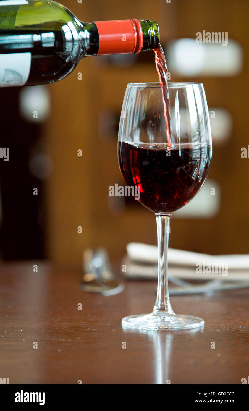 Red wine being poured into a wine glass. Stock Photo