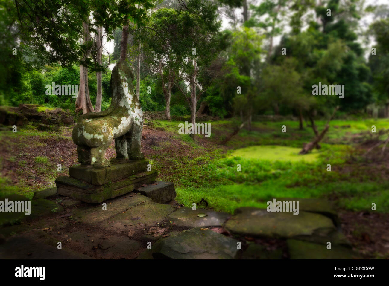 A stone creature, covered in moss and colored with age, stands as silent witness among the ruins of Preah Khan. Stock Photo