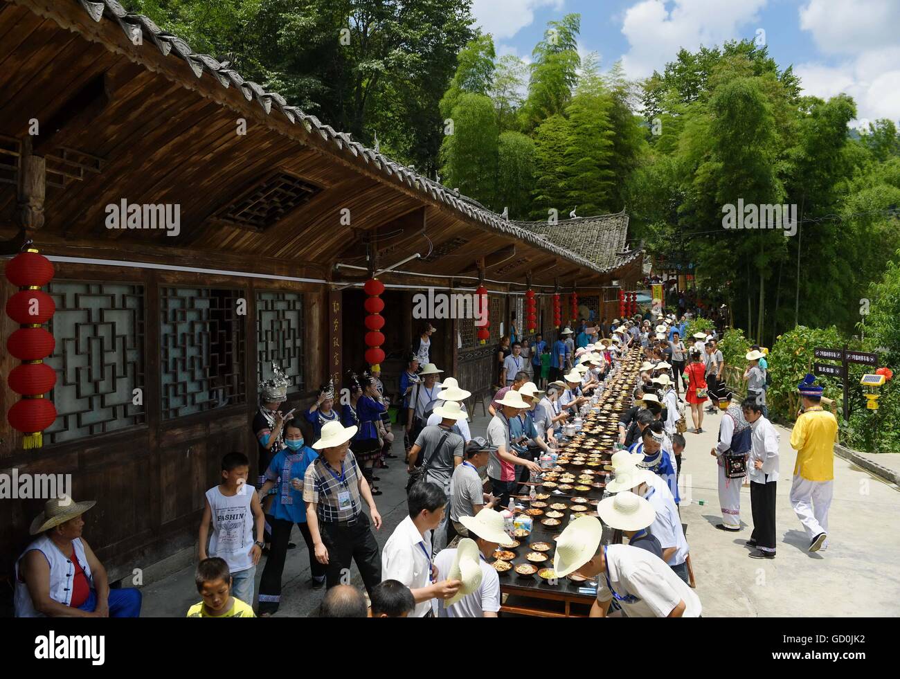 Xuan'en, China's Hubei Province. 9th July, 2016. People gather to enjoy a meal during a 'Helong Banquet' at an ancient Dong Village in Xiaoguan Dong Ethnic Township of Xuan'en County, central China's Hubei Province, July 9, 2016. 'Helong Banquet,' a banquet in which invited people gather to eat meals along a long table, is the highest etiquette for Dong people to serve guests. © Song Wen/Xinhua/Alamy Live News Stock Photo