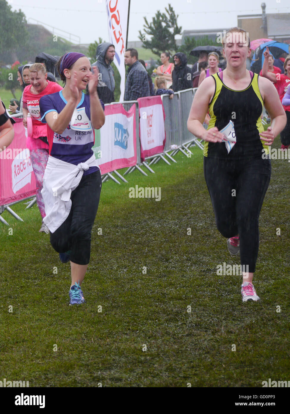 Portsmouth, Hampshire, UK. 10 July 2016. A Runner enourages her friend across the finish line at the end of the Race for life. The Race for life is a charity event in which females complete a 10Km or 5Km run in aid of cancer research. Credit:  simon evans/Alamy Live News Stock Photo
