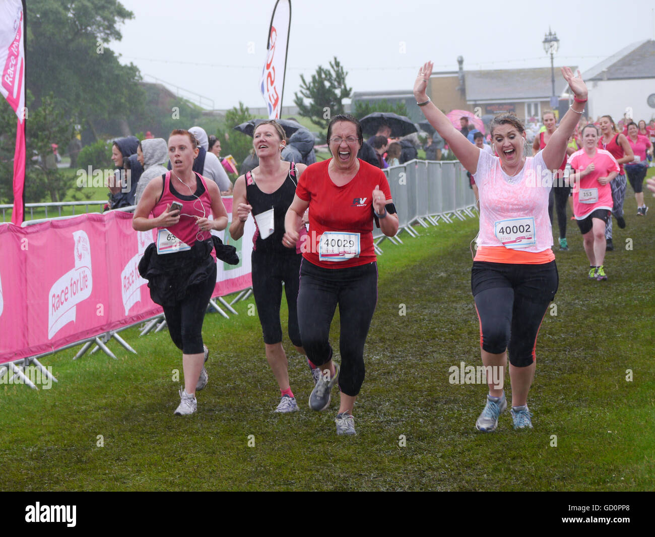 Portsmouth, Hampshire, UK. 10 July 2016. Two friends celebrate as they cross the finish line of the Race for life. The Race for life is a charity event in which females complete a 10Km or 5Km run in aid of cancer reseach. Credit:  simon evans/Alamy Live News Stock Photo