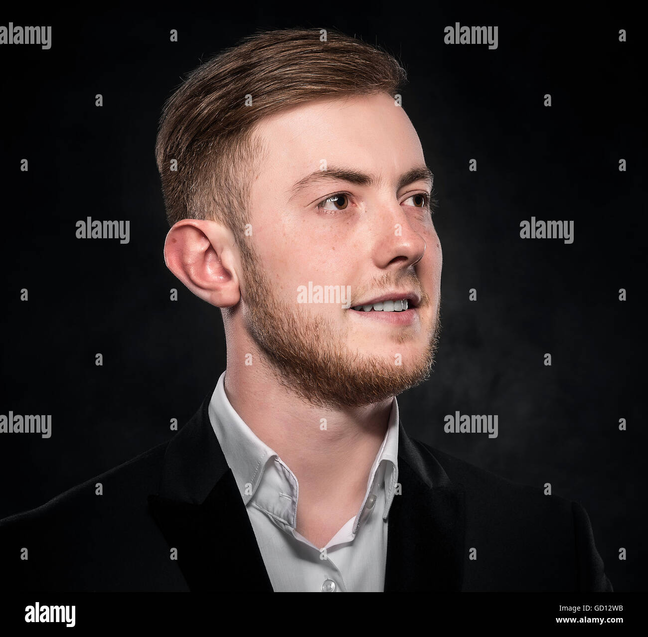 Young handsome man in suit smiling on dark background Stock Photo - Alamy