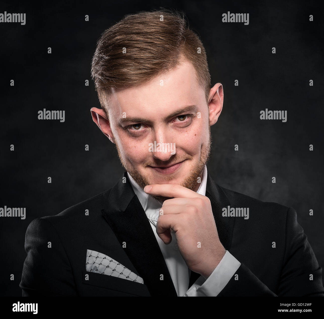 Young handsome man in suit smiling on dark background Stock Photo - Alamy