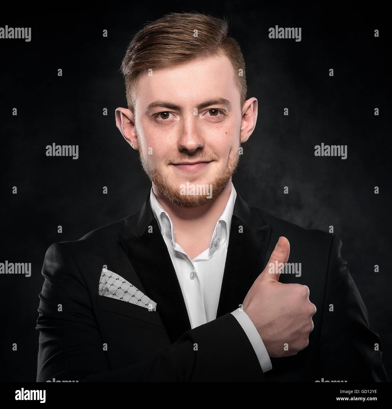 Young handsome man in suit smiling on dark background Stock Photo - Alamy