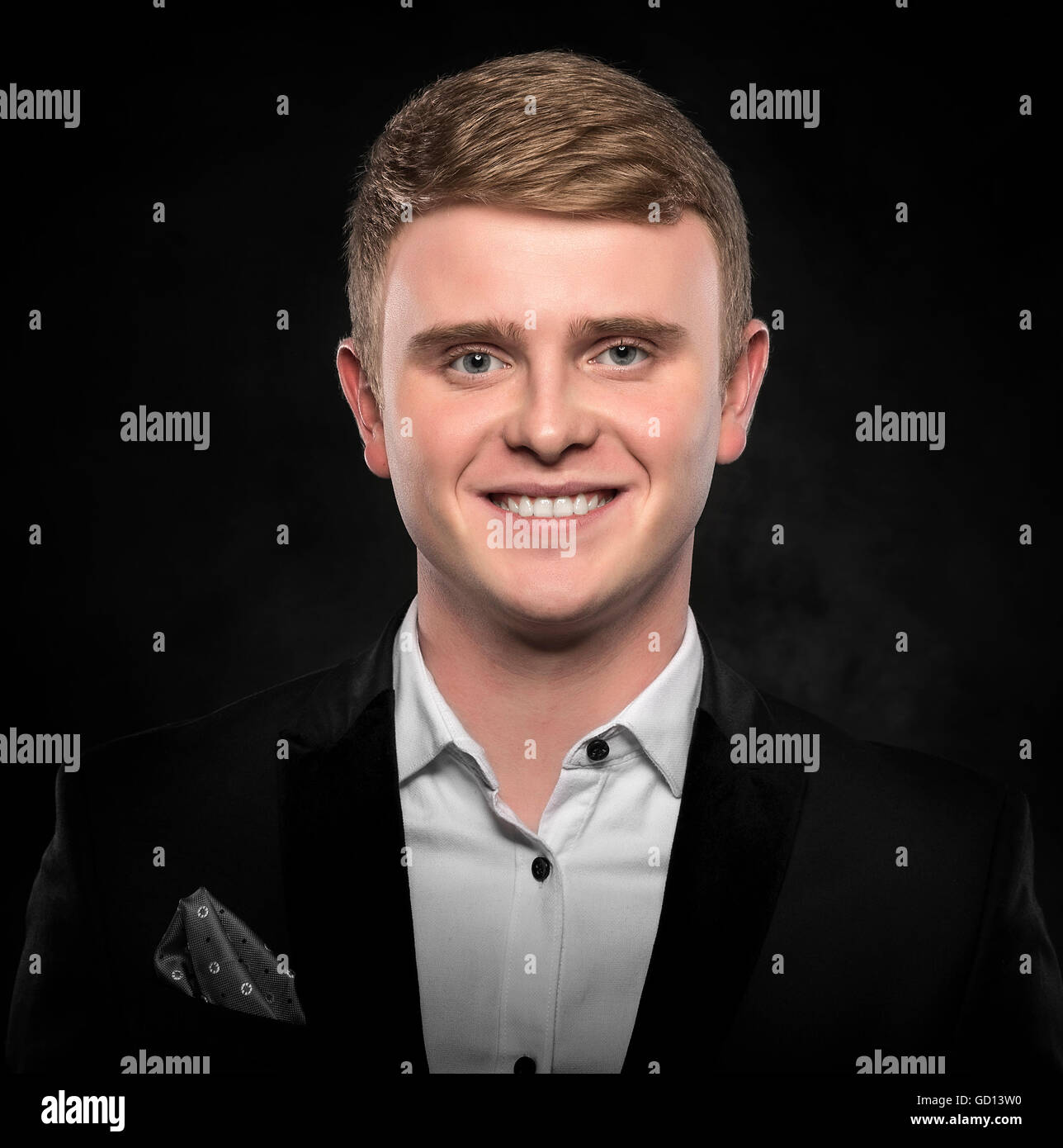 Young handsome man in suit smiling on dark background Stock Photo - Alamy