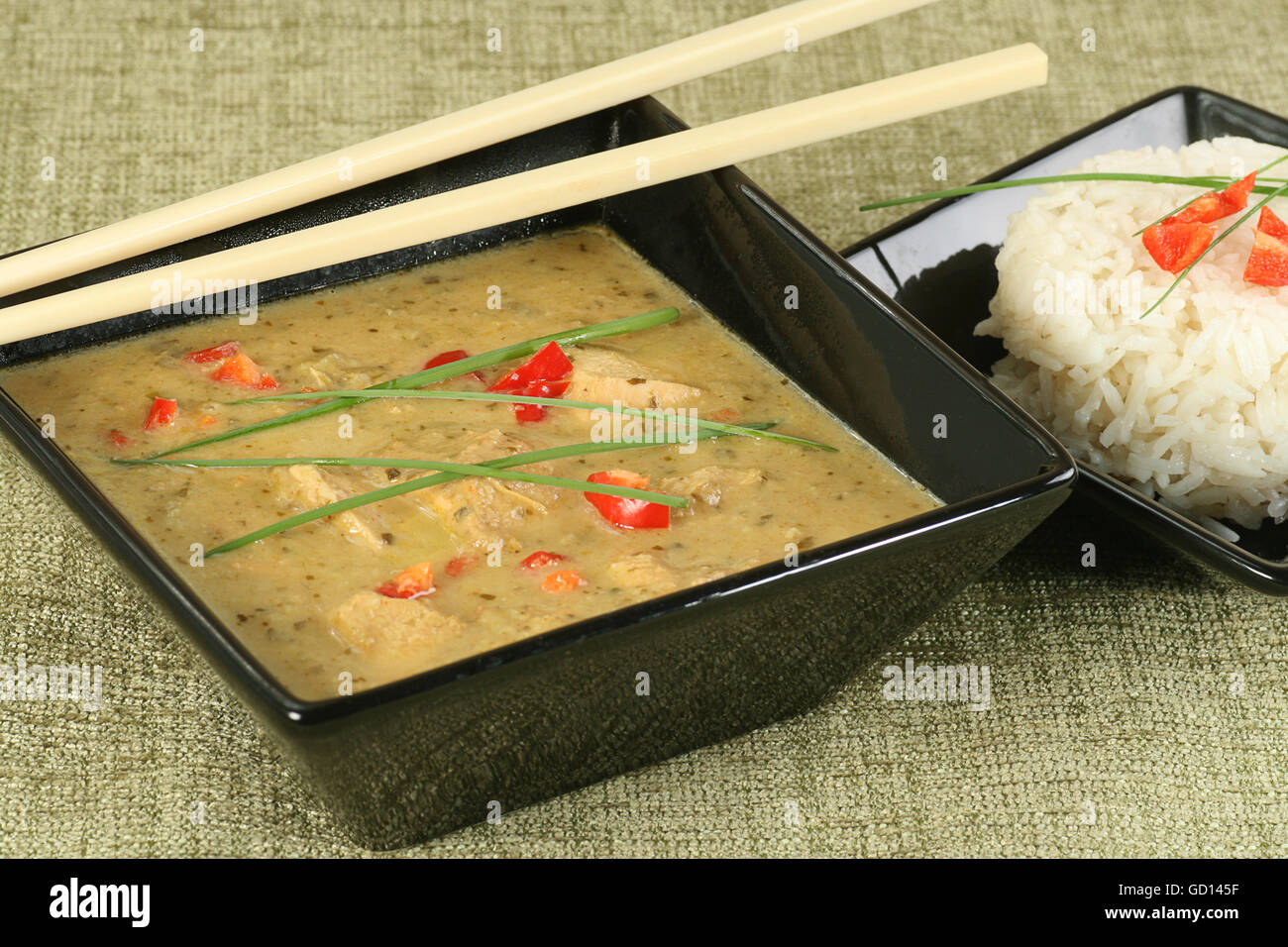 bowl of thai green chicken curry with garnish and sticky rice Stock