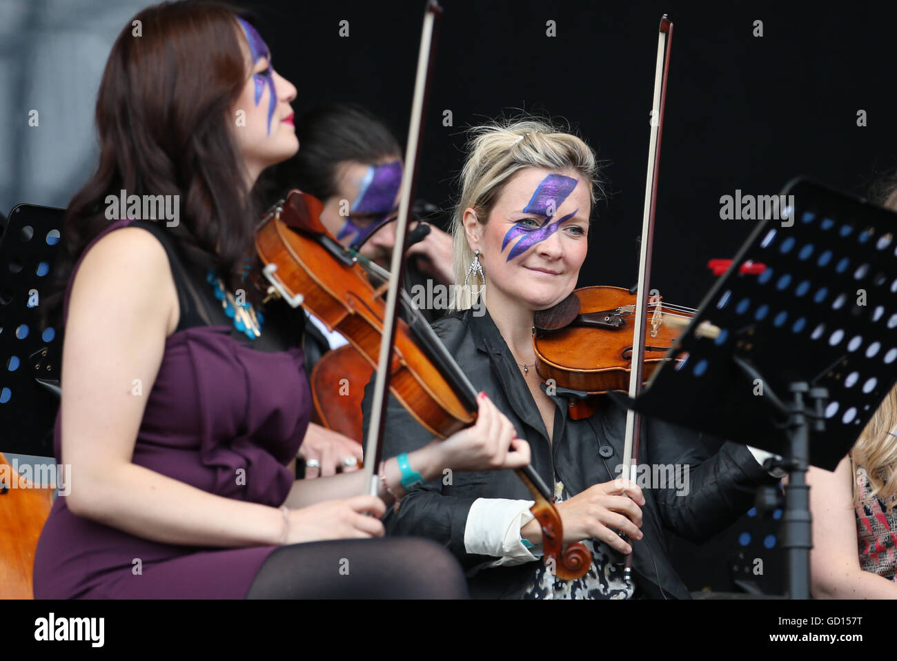 Members of the Rogue Orchestra with faces painted like Ziggy Stardust perform a David Bowie tribute set on the main stage during the third day of T in the Park, the annual music festival held at Strathallan Castle, Perthshire. Stock Photo