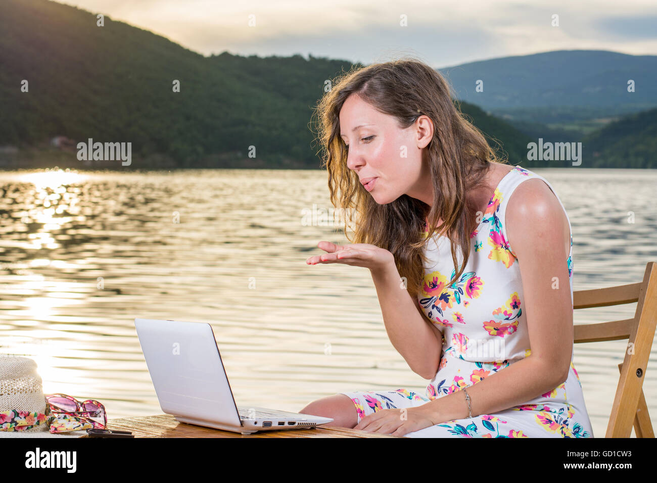 Young woman having a video call by the lake Stock Photo