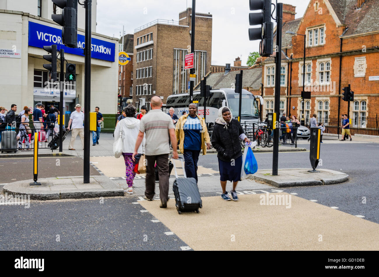 People cross the road at a pedestrian crossing outside Victoria Coach Station. Stock Photo