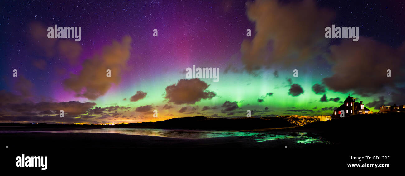 A strong solar storm creates a bright display of the northern lights over Beadnell Bay in Northumberland. Stock Photo