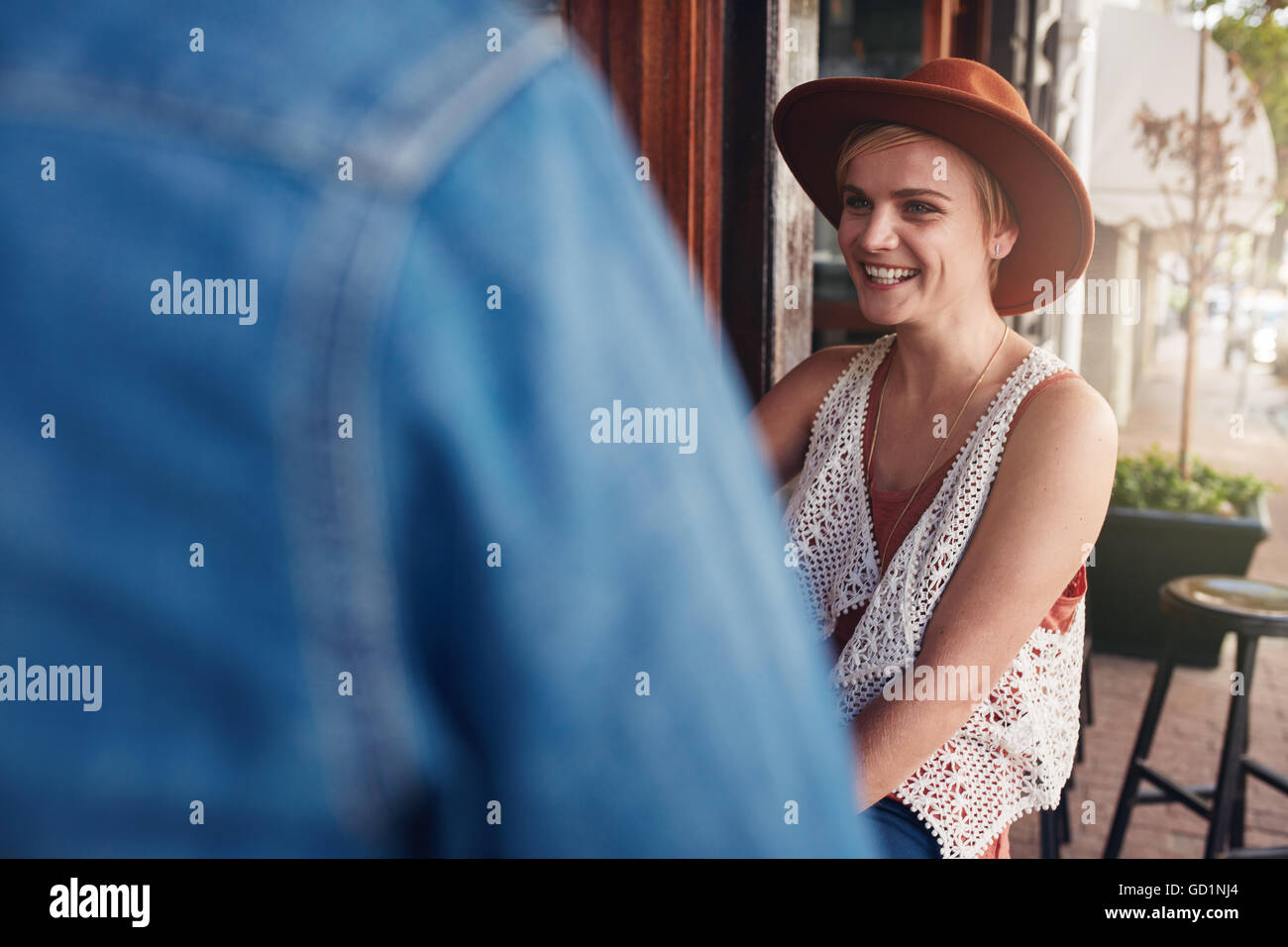 Smiling young woman sitting at a coffee shop with her friend. Young people sitting at a cafe table. Stock Photo