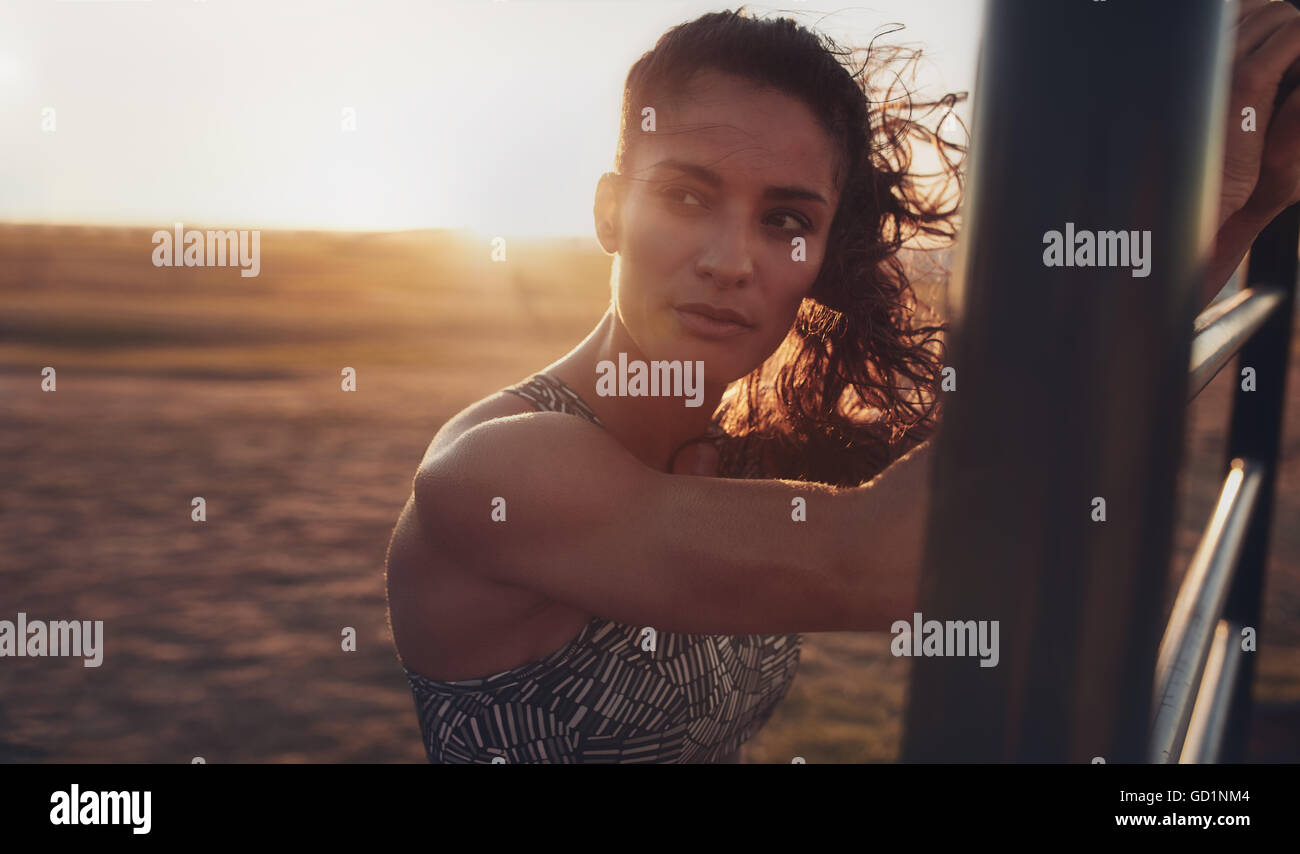 Close up portrait of determined young woman standing on the beach and looking away during evening. fitness woman working out at Stock Photo