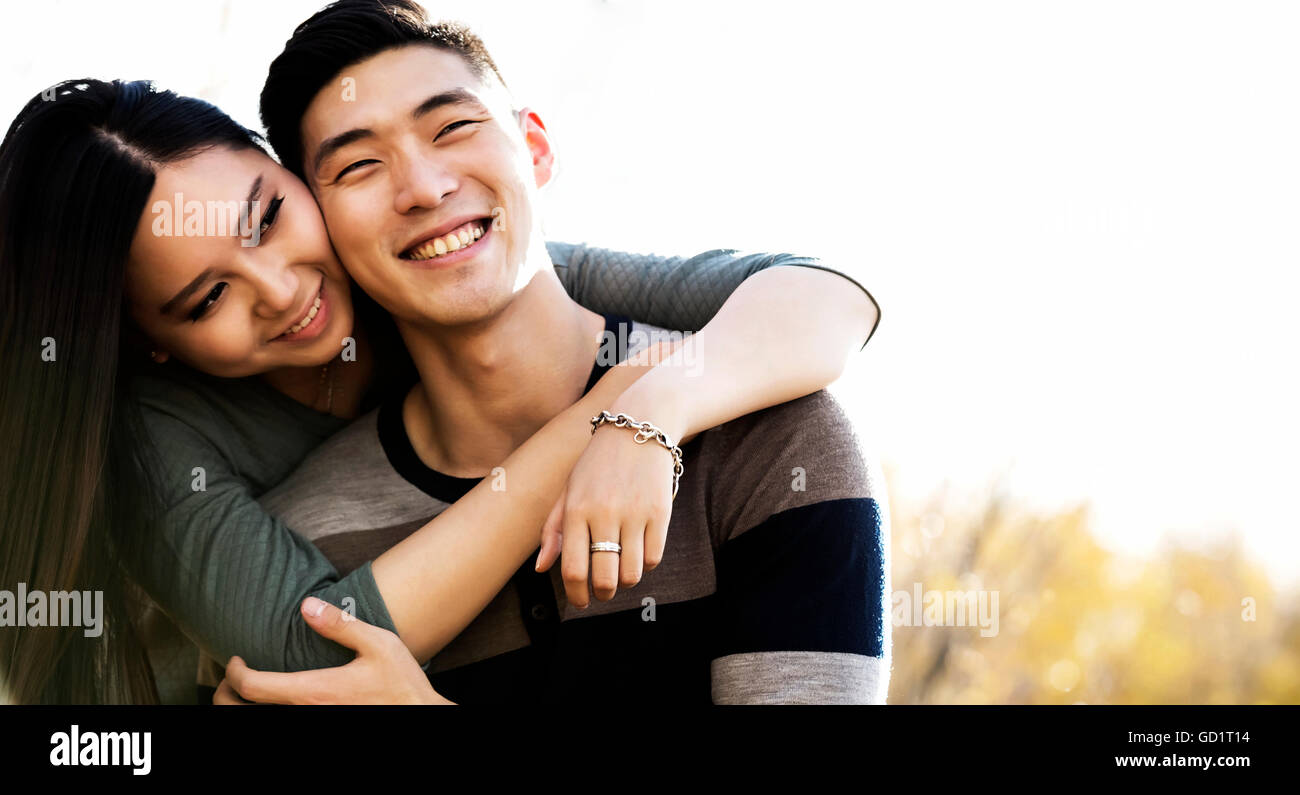 A Young Asian Couple Enjoying Quality Time Together Outdoors In A Park  In Autumn And Embracing Each Other In The Warmth Of The Sunlight During The... Stock Photo