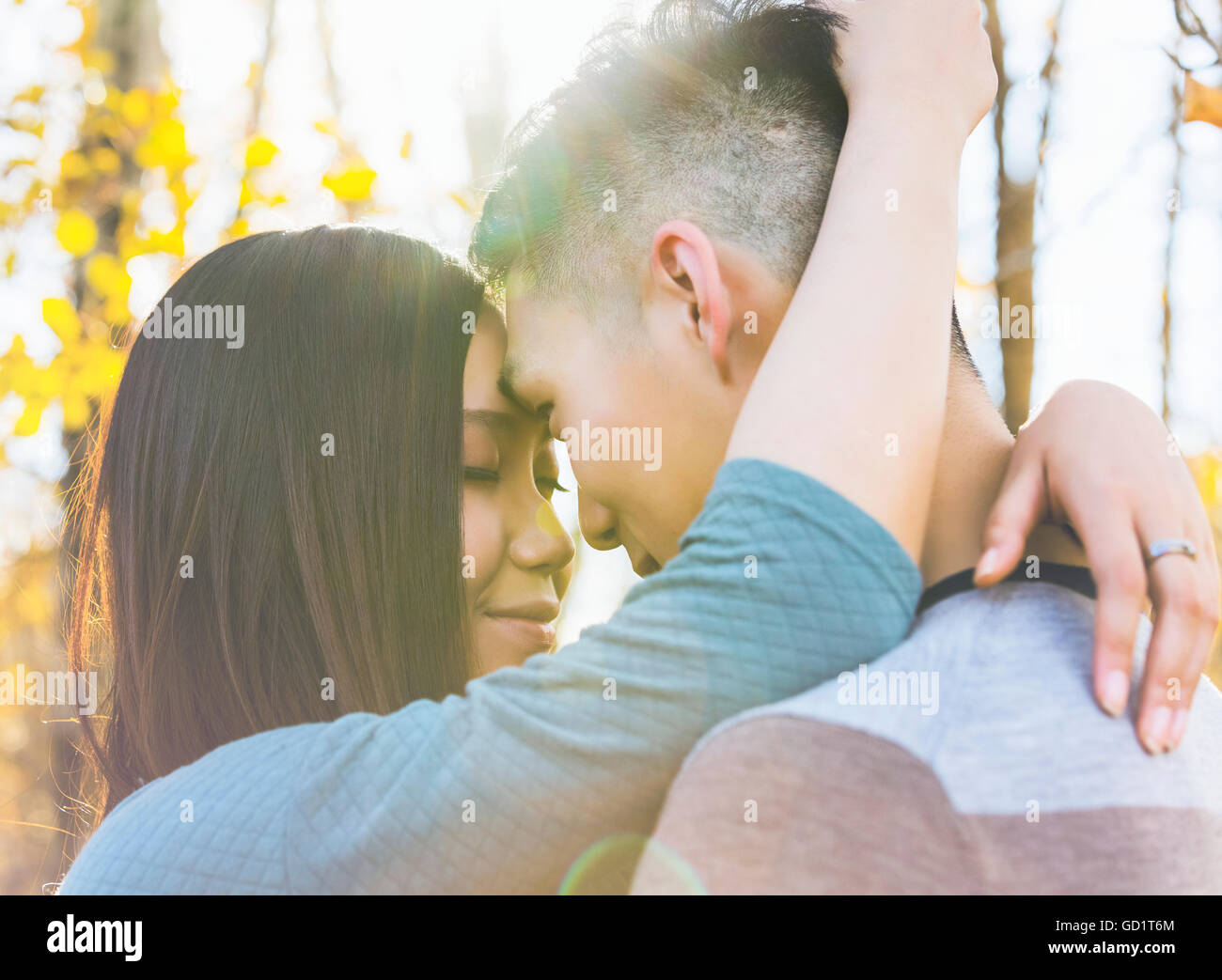 A young Asian couple enjoying quality time together in a park in autumn ...