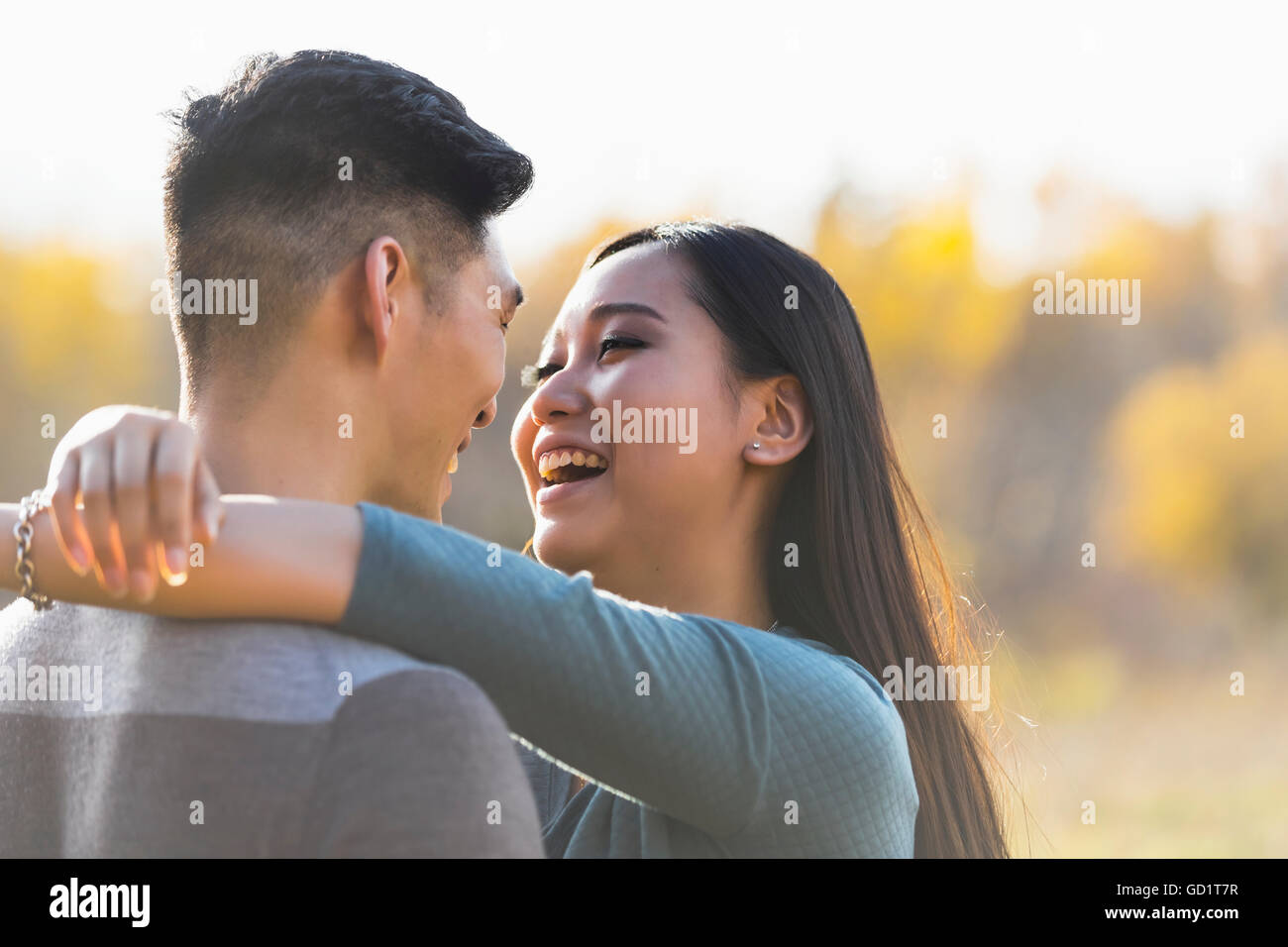 A Young Asian Couple Enjoying Quality Time Together Outdoors In A Park In Autumn And Embracing Each Other In The Warmth Of The Sunlight During The ... Stock Photo