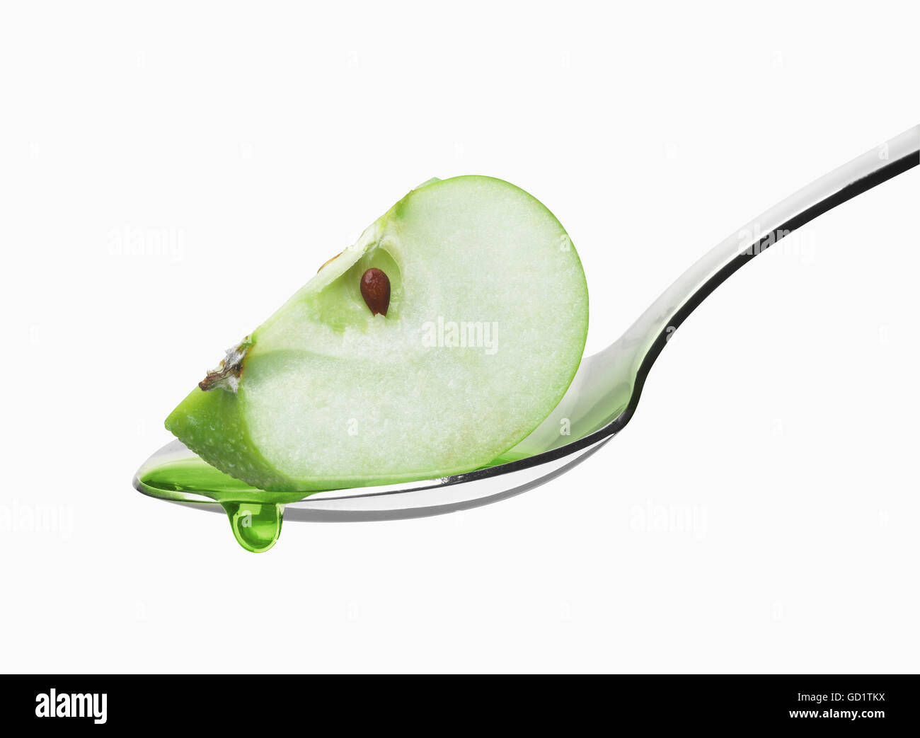 Wedge of a green apple in a spoon against a white background; Toronto, Ontario, Canada Stock Photo