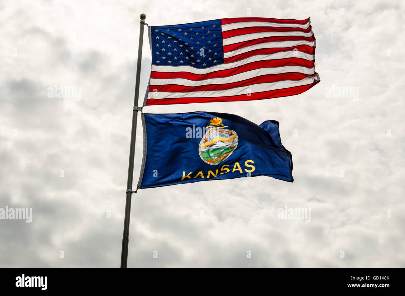 United States and Kansas flags blowing in the wind against a cloudy sky Stock Photo