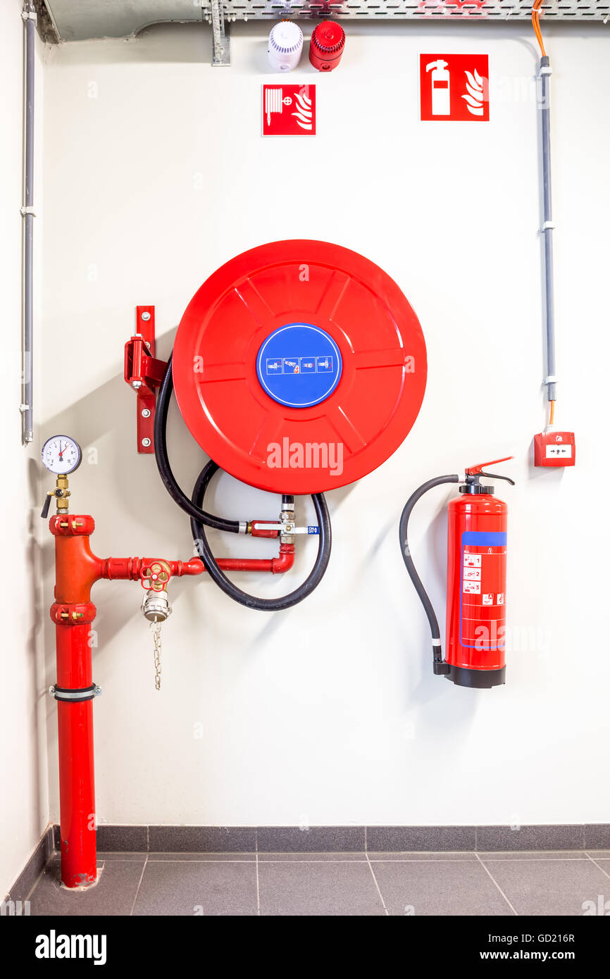 an fire hose hanging on the wall and powder extinguisher Stock Photo