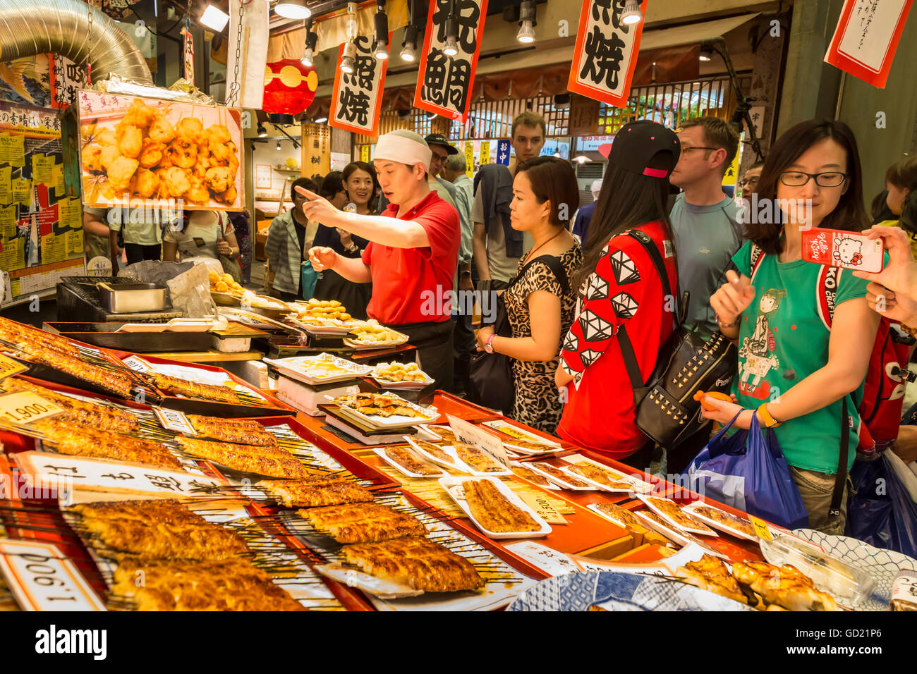 Customers queue at busy local Japanese teriyaki food stall, Nishiki Market (Kyoto's Kitchen), Downtown Kyoto, Japan, Asia Stock Photo