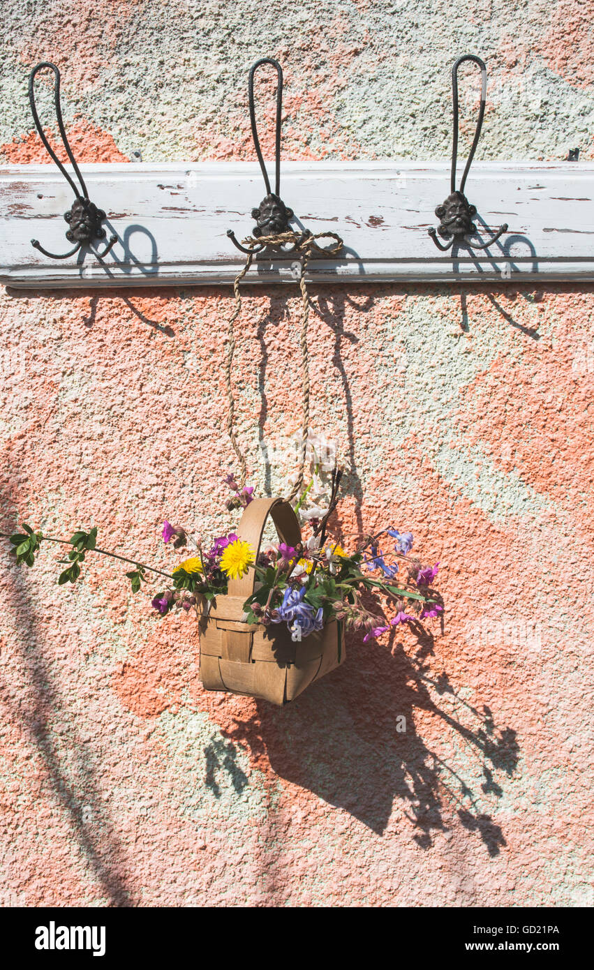 Flowers in the basket on hanger on a wall. Sunlight Stock Photo
