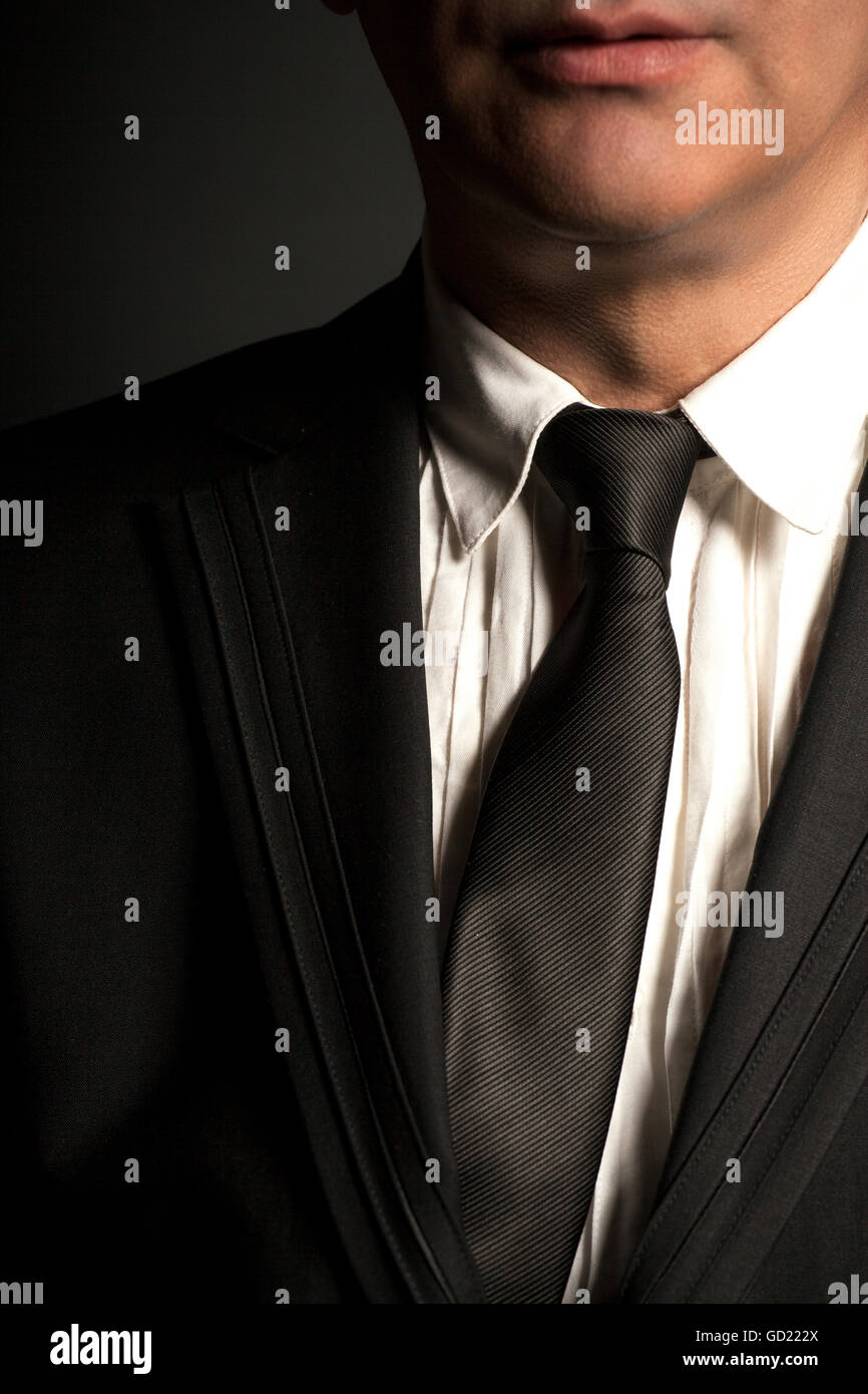 Man in black suit and black tie on a black background Stock Photo - Alamy