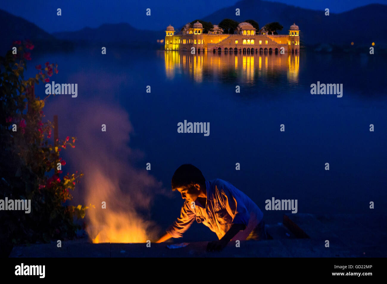Boy cooking at twilight by the Jal Mahal Floating Lake Palace, Jaipur, Rajasthan, India, Asia Stock Photo