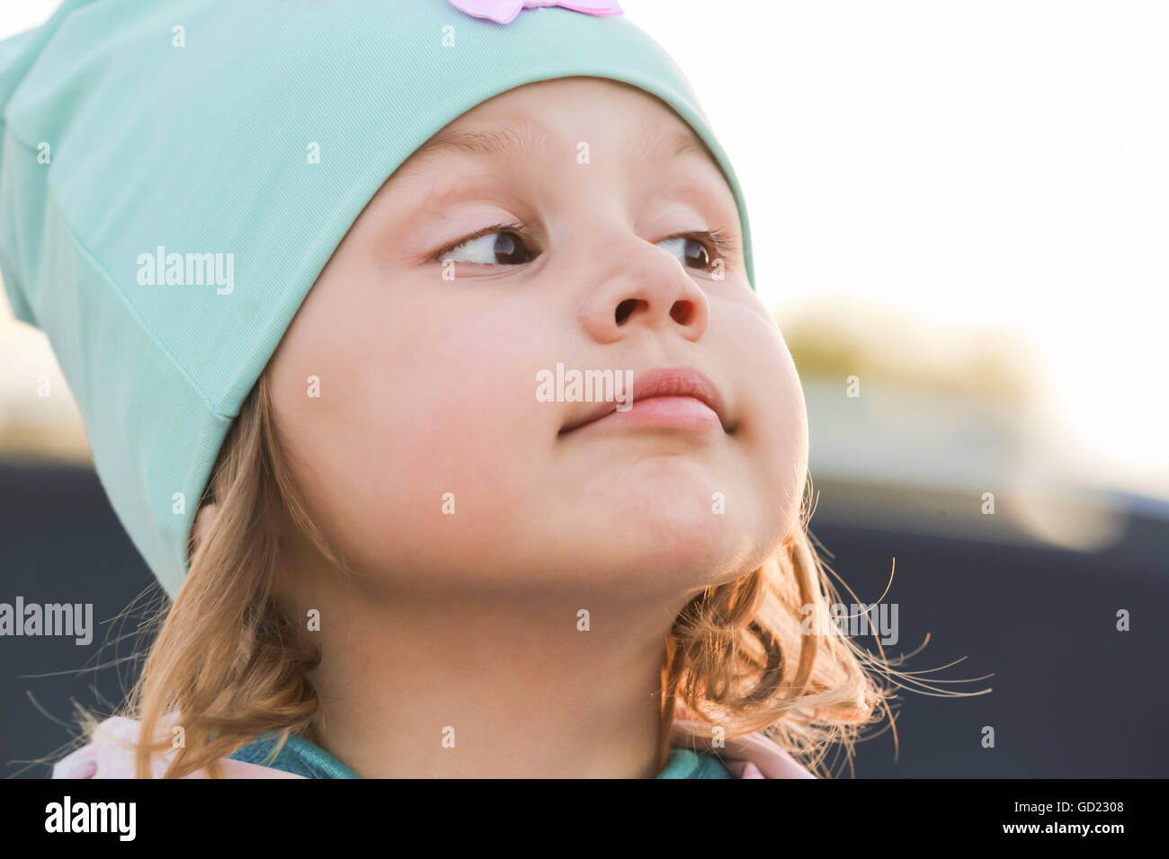 Closeup face portrait of funny cute Caucasian blond baby girl in green hat Stock Photo