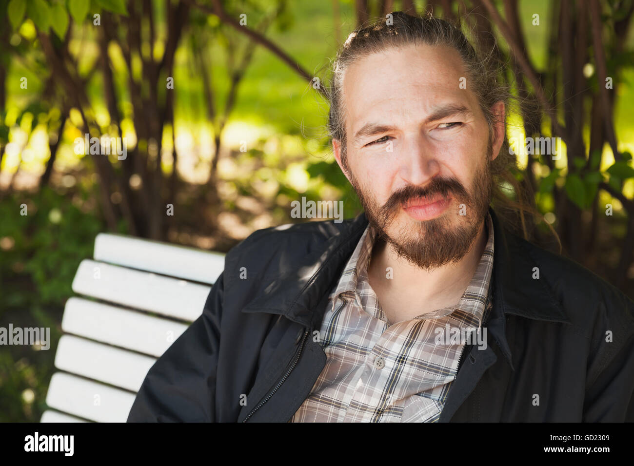 Outdoor portrait of young bearded Asian man in bright summer park Stock Photo