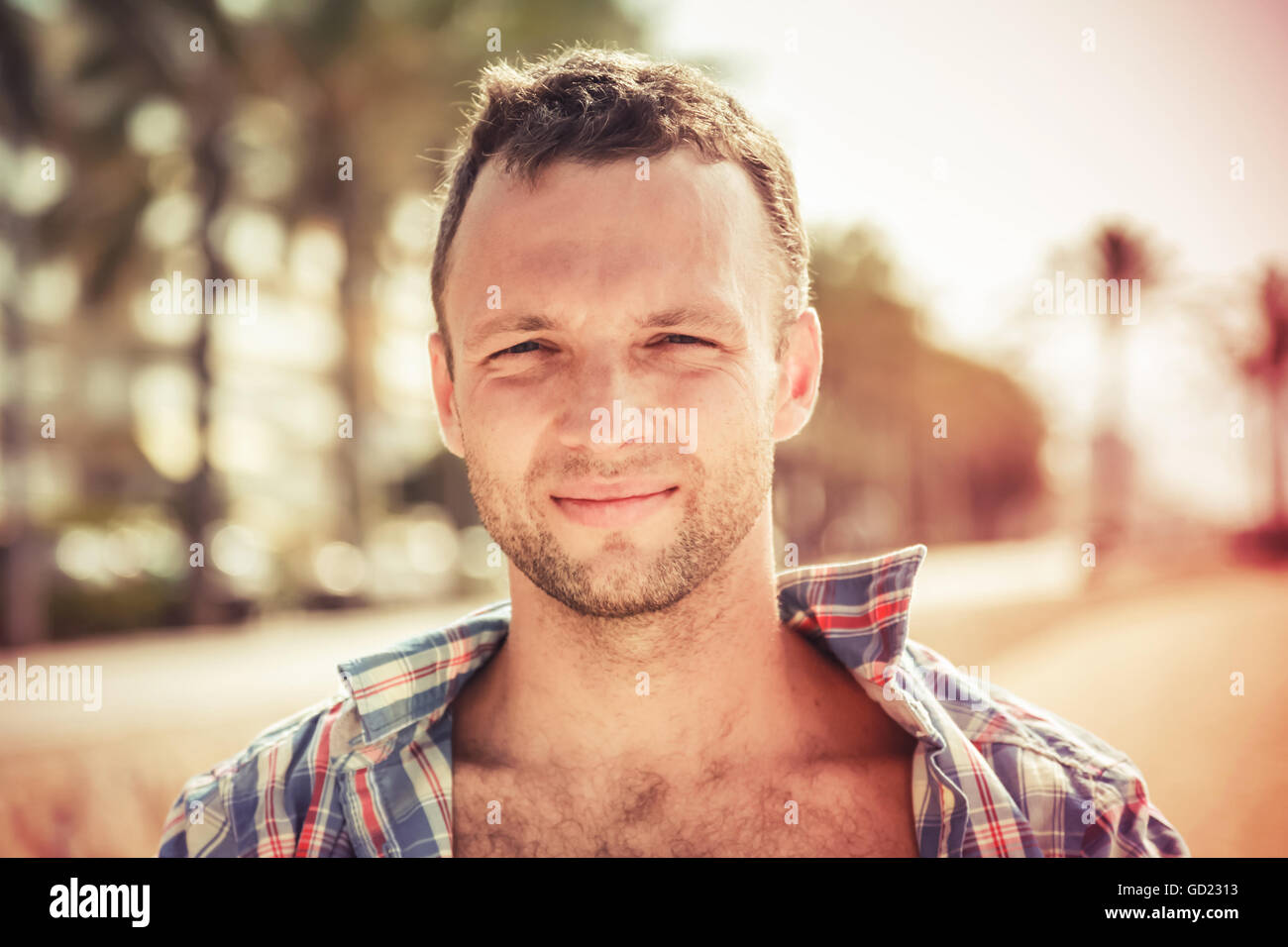 Smiling young handsome Caucasian man, outdoor portrait in sunny day, vintage tonal correction photo filter, old style effect Stock Photo
